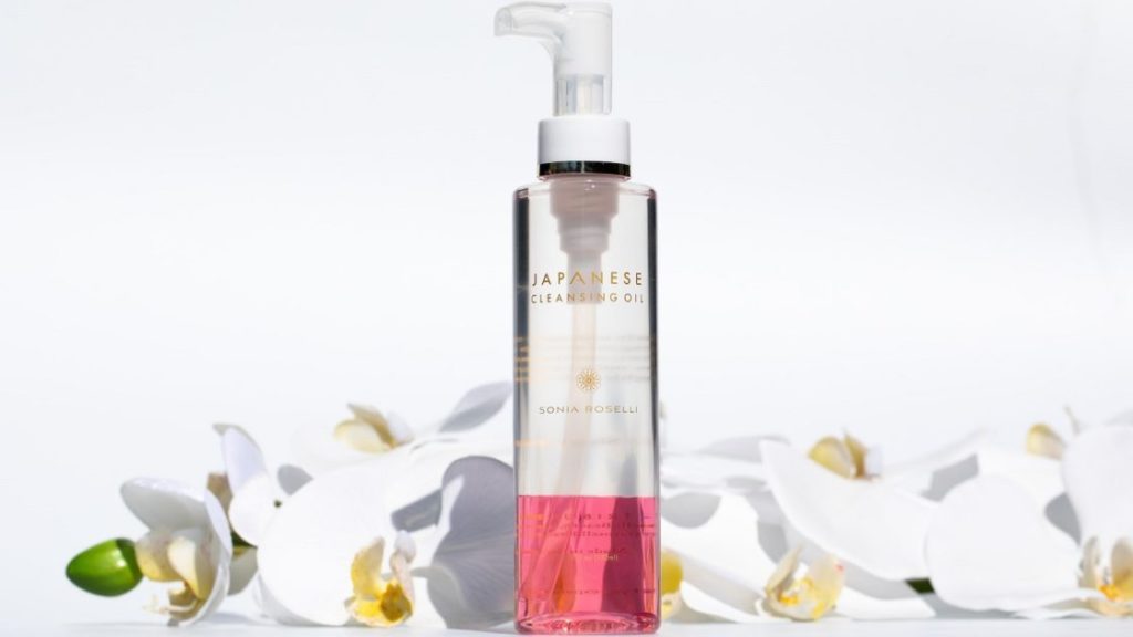 白いランの花の前にピンクのクレンジングオイルが入った透明ののボトル